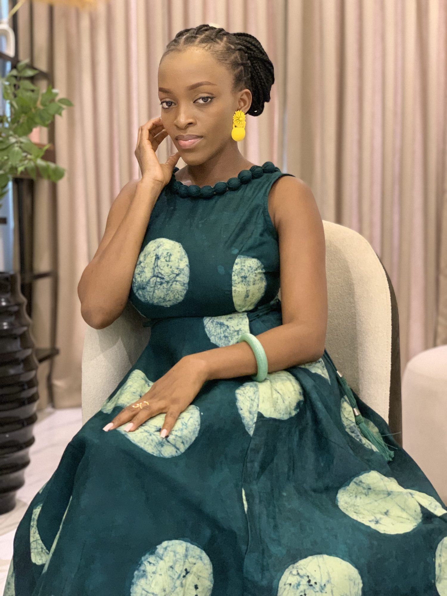 Model seated in AFẸ́FẸ́ I, teal Àdìrẹ with pale moon circles